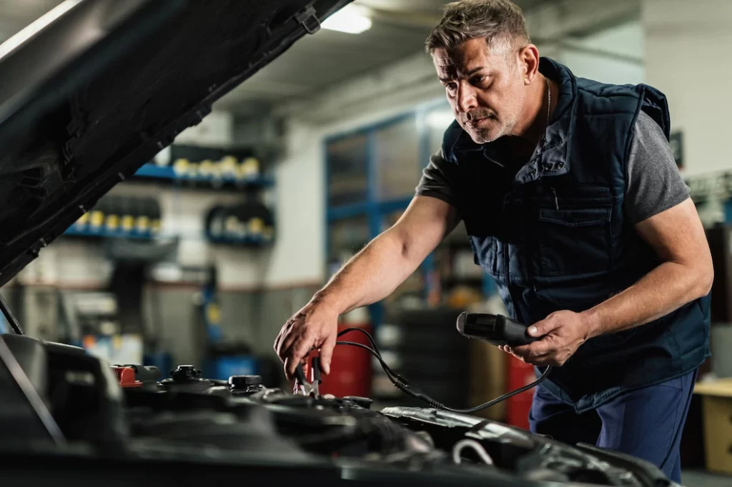 mid-adult-mechanic-using-diagnostic-tool-while-checking-voltage-car-battery-auto-repair-shop_637285-4265