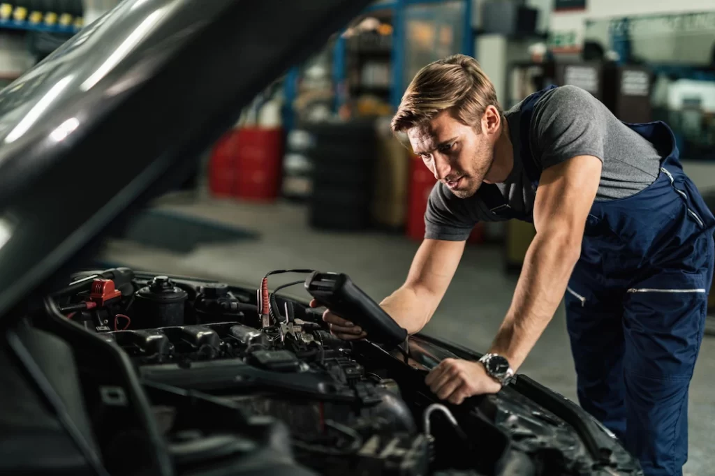 young-mechanic-with-diagnostic-tool-analyzing-car-engine-problem-auto-repair-shop_637285-4271